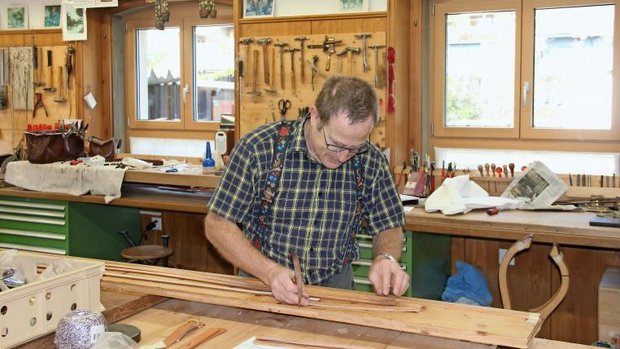 Hansruedi Blaser schneidet Riemen für ein Zaumzeug zu.