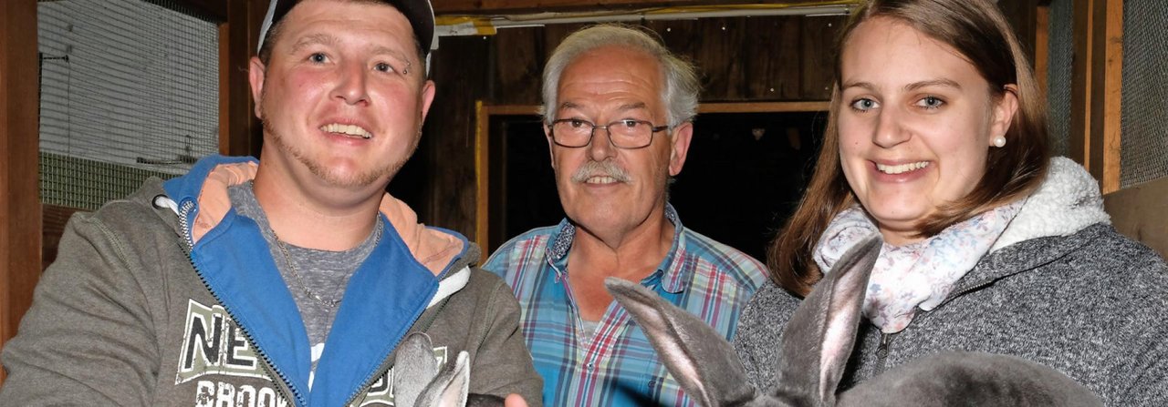 Urs Messerli, Walter Küng und Kimberly Schwab (v.?l.) posieren mit einem Kleinrex chinchillafarbig und einem Blaurex.