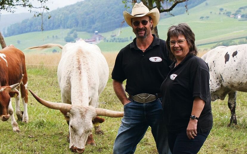 Urs und Daniela Weiss inmitten ihrer Tiere auf einer Weide der Texas Longhorn Ranch.