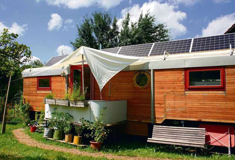 Der Zirkuswagen steht hinter einem Bauernhaus mit Blick ins Grüne.