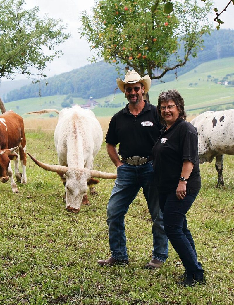 Urs und Daniela Weiss inmitten ihrer Tiere auf einer Weide der Texas Longhorn Ranch.